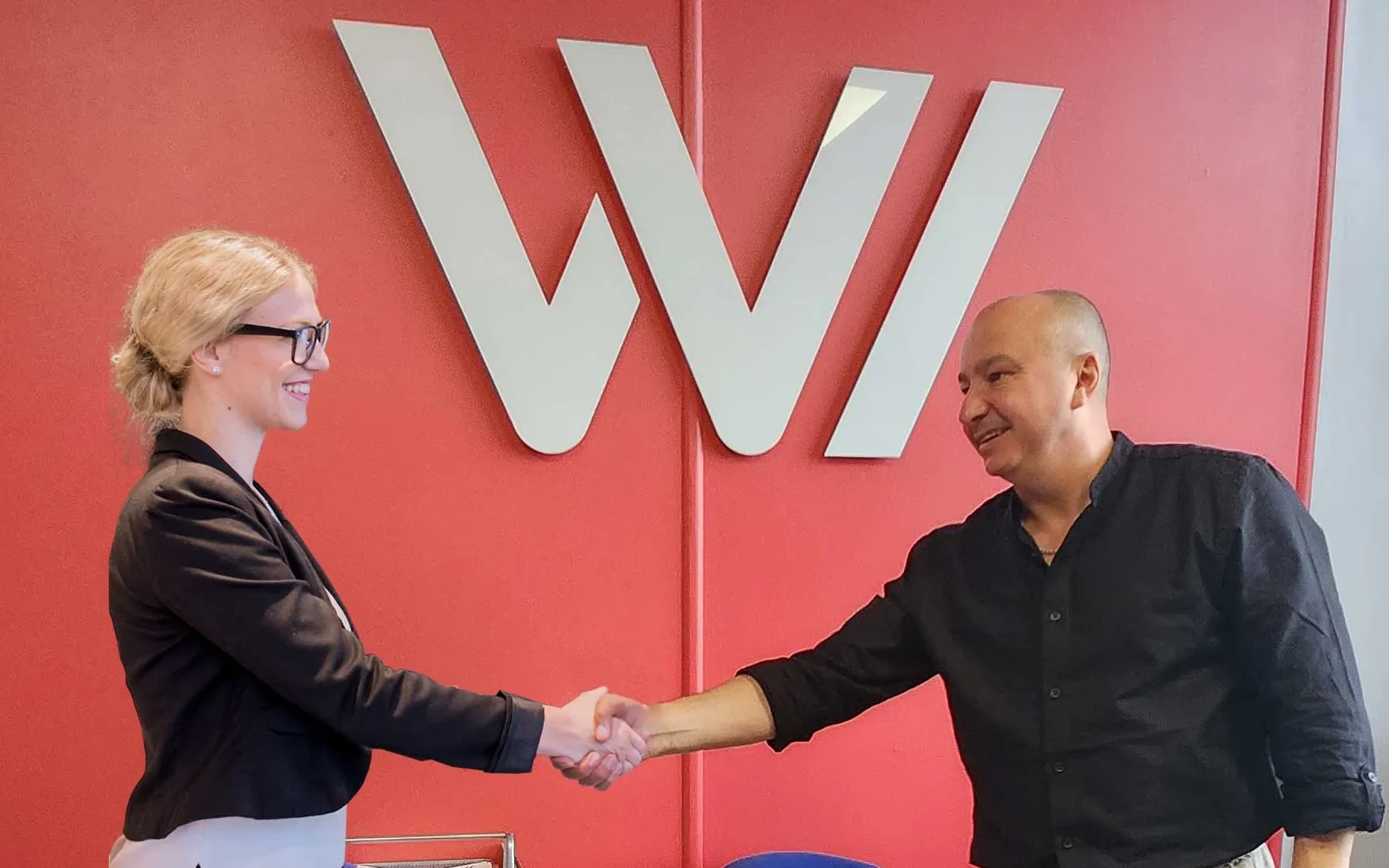 Kevin from Web Design MK shaking hands with a client in front of the Web Design MK logo